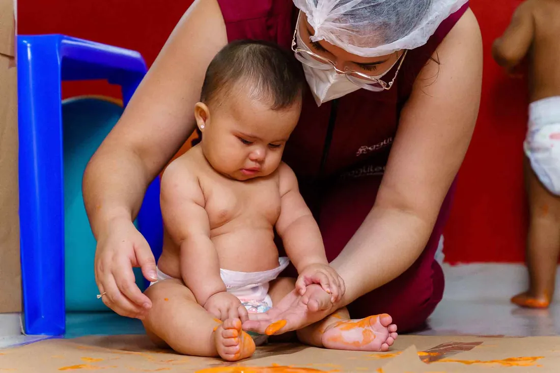 Bebê sendo cuidado por uma educadora