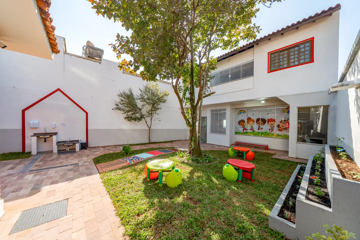 Pátio externo com jardim, árvores e piso de tijolinhos
