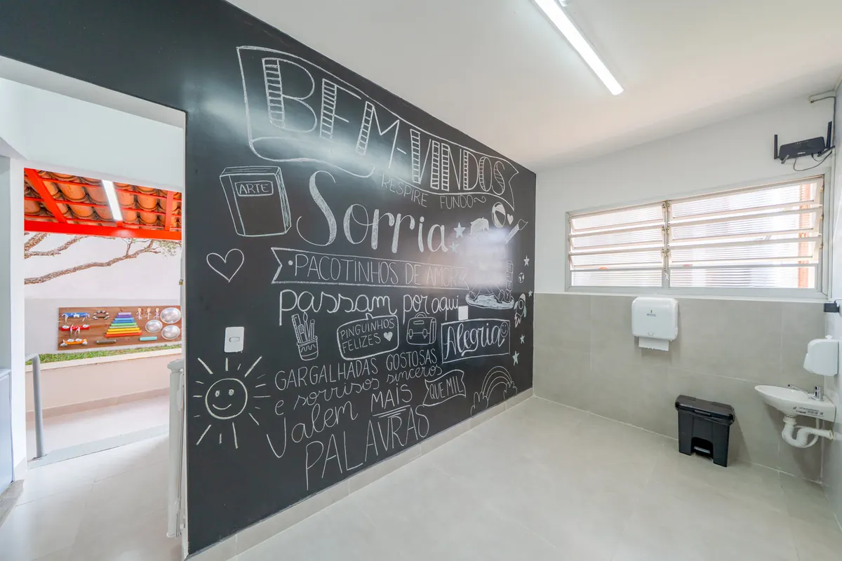 Sala de arte com parede de lousa e mural de criança pintando
