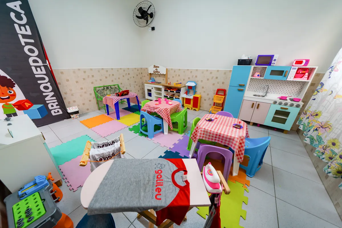 Brinquedoteca com cozinha de brinquedo, mesinhas e piso de EVA colorido