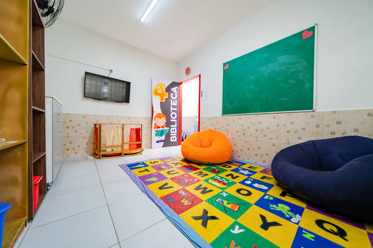 Biblioteca com tapete de letras, pufes e estante de livros